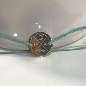 Bracelet plaque ronde 2 trous avec cordon réglable gravé avec lune, étoiles et lettres en braille.
